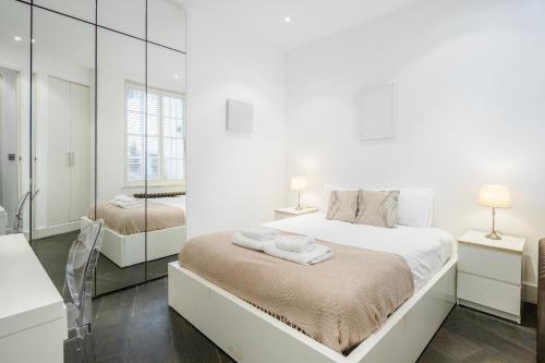 a white bedroom with a large bed and a mirror at Beautiful 2 bedroom Covent Garden apartment in London