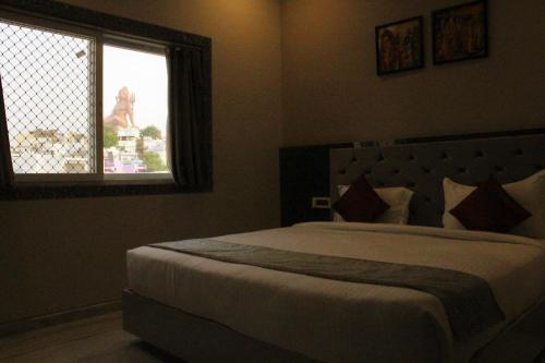Un dormitorio con una cama grande y una ventana en Hotel Shri Anand Dham, Nathdwara - 125 Meters away from the temple, en Nathdwara