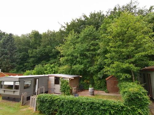 una caravana estacionada en un patio junto a los árboles en Puur genieten chalet met patio, bos en bosbad, en Havelte