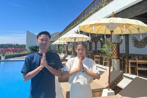 a man and a woman standing in front of a pool praying at Sea La Vie Resort Nusa Penida in Nusa Penida