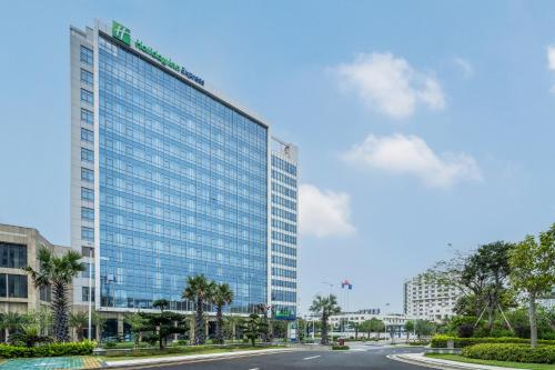 um grande edifício de vidro com uma estrada em frente em Holiday Inn Express Beihai Silver Beach, an IHG Hotel em Beihai