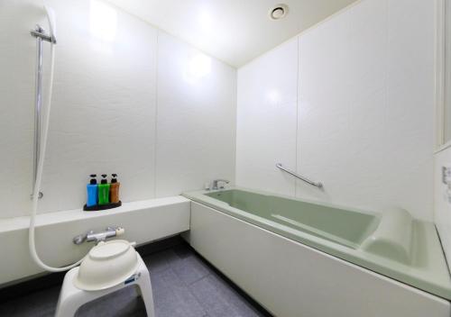 a white bathroom with a tub and a toilet at Kamogawa Grand Tower in Kamogawa