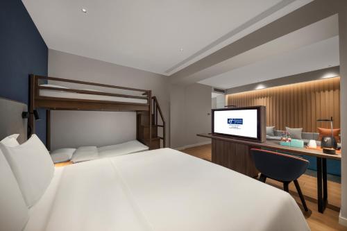 a bedroom with a bed and a desk with a tv at Holiday Inn Express Beihai Silver Beach by IHG in Beihai