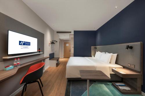 北海市にあるHoliday Inn Express Beihai Silver Beach, an IHG Hotelのベッド1台、薄型テレビが備わるホテルルームです。