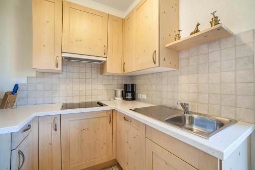 uma cozinha com armários de madeira e um lavatório em Hof am Schloss Apartment Edelweiss em Montechiaro