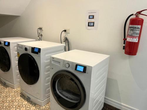 two washing machines in a laundry room with a fire extinguisher at Anwari Hotel in Bangkok