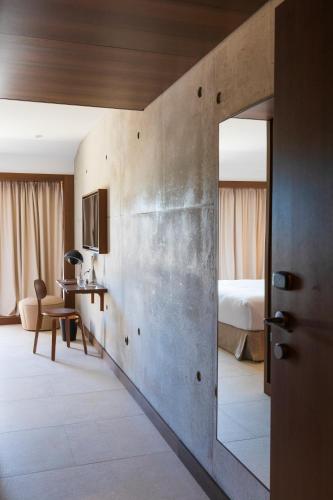 Una habitación de hotel con un espejo y un dormitorio. en Hôtel Spa & Restaurant - Son de Mar, en Porto Vecchio