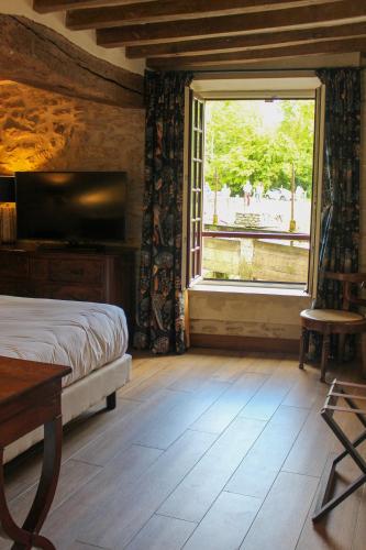 a bedroom with a bed and a large window at Moulin de Fourges in Fourges