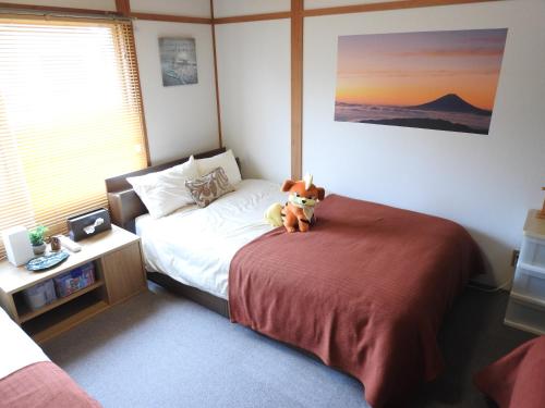 um urso de peluche sentado numa cama num quarto em 旭川貸切一軒家プラスティ em Asahikawa