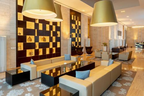 Un vestíbulo con un sofá, mesas y sillas. en Radisson Blu Residence, Dubai Marina, en Dubái