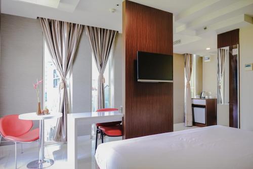 a hotel room with a bed and a desk and a tv at Empress Hotel Makassar City Center by LIFE in Makassar