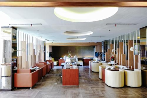 un vestíbulo de un restaurante con mesas y sillas en Empress Hotel Makassar City Center by LIFE, en Makassar