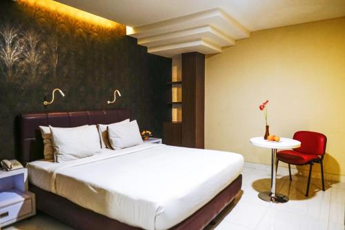 a bedroom with a bed and a red chair at Empress Hotel Makassar City Center by LIFE in Makassar