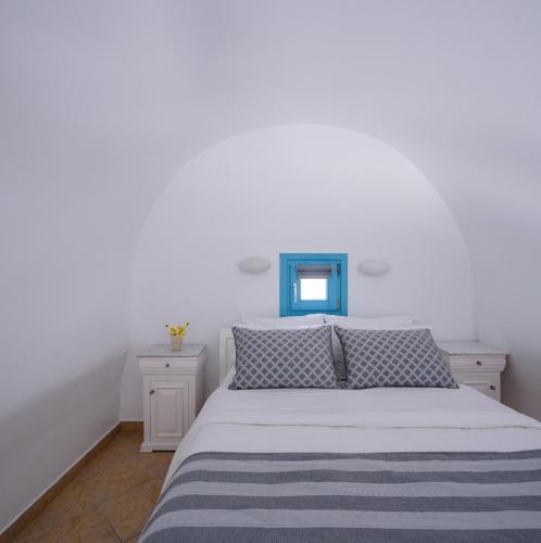 a white bedroom with a bed and a blue window at Kalestesia Suites in Akrotiri