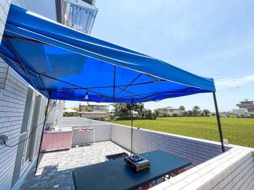 三星鄉的住宿－遇稻包棟民宿，露台上的蓝色遮阳伞和桌子
