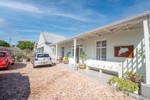 a white house with a car parked in the driveway at The Lookout Guest House in Port Alfred