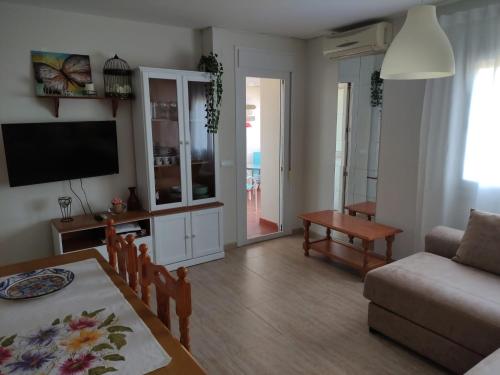 sala de estar con mesa, sofá y TV en Carvajal - Balcon de Benalmadena, en Benalmádena