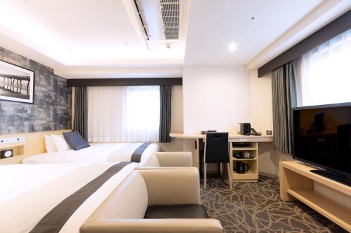 a hotel room with two beds and a flat screen tv at Hotel Actel Nagoya Nishiki in Nagoya