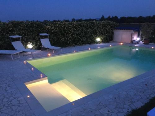 a swimming pool at night with chairs around it at il leccio in San Lazzaro di Savena