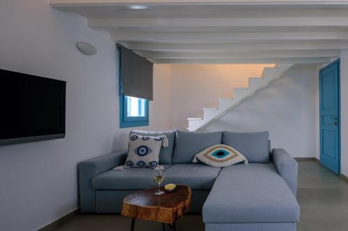 a living room with a blue couch and a staircase at Kalestesia Suites in Akrotiri