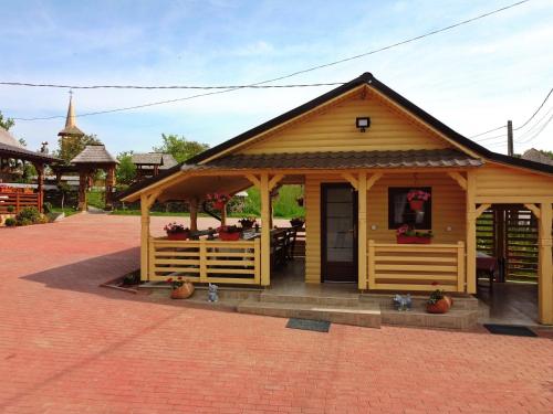 a small wooden building with a porch and a table at Pensiunea Inima Maramureșului in Breb