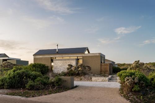 a brick house with a black roof at Romansbaai Collection in Gansbaai