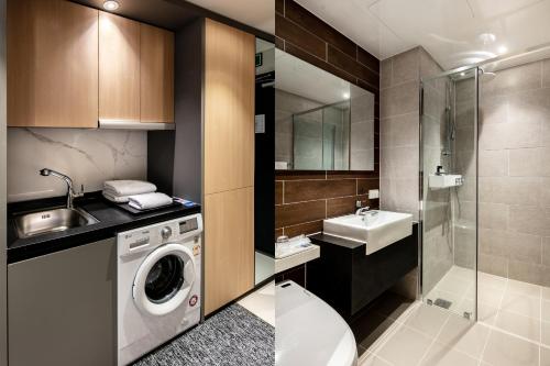 a bathroom with a washing machine and a sink at Icheon Skysun Hotel in Icheon