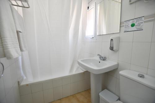 a white bathroom with a sink and a bath tub at HB Torrevieja in Torrevieja