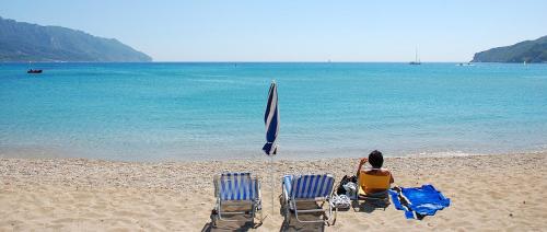 twee stoelen en een parasol op een strand bij Villa Lucia in Agios Georgios Pagon