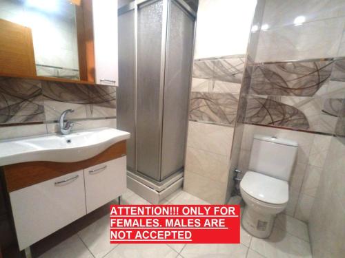 ein Badezimmer mit einer Toilette und einem Waschbecken mit einem roten Schild in der Unterkunft !ONLY FEMALES! Bakirkoy Ladies Dormitory in Istanbul