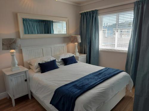 a bedroom with a large white bed with blue pillows at Belle View @ Knysna Quays in Knysna