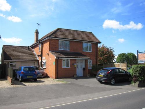 a brick house with two cars parked in the driveway at Belle Vue Guesthouse in Glastonbury
