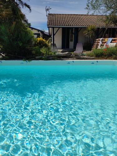 une grande piscine d'eau bleue devant une maison dans l'établissement chambre indépendante, à Gujan-Mestras