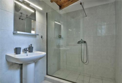 a white bathroom with a shower and a sink at Villa Melina in Nisaki