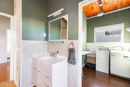 een badkamer met een wastafel en een wasmachine bij Couches, Bar Table & Kawau View in Snells Beach