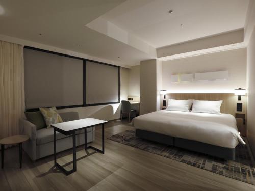 a bedroom with a bed and a table and a couch at Hyatt Place Kyoto in Kyoto