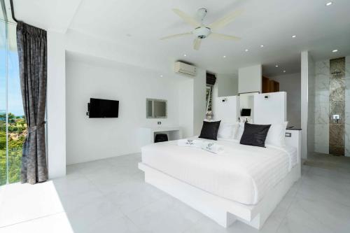 ein weißes Schlafzimmer mit einem großen weißen Bett und einem Fenster in der Unterkunft Villa Yindee managed by Villa For You in Koh Samui 