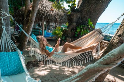 a woman laying in a hammock on the beach at Cili Emas Oceanside Resort in Tejakula