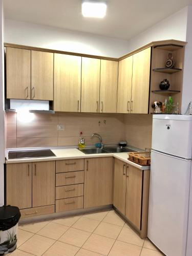 a kitchen with wooden cabinets and a white refrigerator at Beach Apartments Durres in Durrës