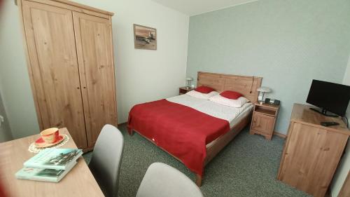 a bedroom with a bed and a desk and a television at Villa Karo in Łeba