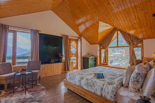 a bedroom with a large bed and a large window at Lost in the Alps by VEO - Part of StayVista in Manāli