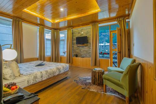 a bedroom with a bed and a chair and a tv at Lost in the Alps by VEO - Part of StayVista in Manāli