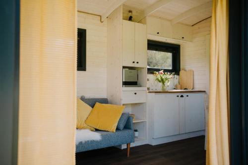 a tiny house with a blue couch and a kitchen at Maringotka Gerlovka Šumava in Čachrov