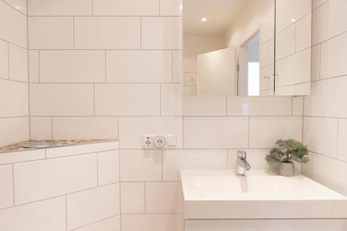 ein weißes Badezimmer mit einem Waschbecken und einem Spiegel in der Unterkunft Miramar Wohnung 312 in Grömitz