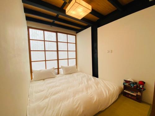 a bedroom with a large white bed with a window at 捉鳳凰 台南百年老宅包棟導覽民宿系列Catchphoenix Centennial Guesthouse in Tainan