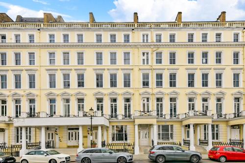 un gran edificio amarillo con coches estacionados frente a él en Lee Abbey London, en Londres