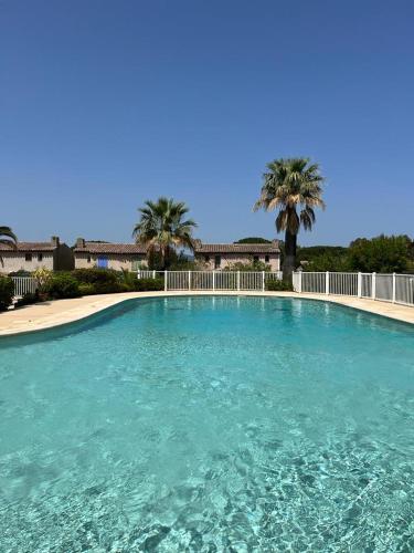 une grande piscine avec de l'eau bleue et des palmiers dans l'établissement L’atypique : 2 chambres // Piscine // parking, à Saint-Tropez