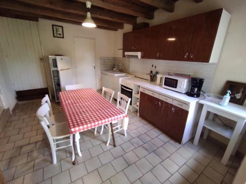 Una cocina con mesa y sillas y un microondas. en gite le vieux perrin, en Andelaroche