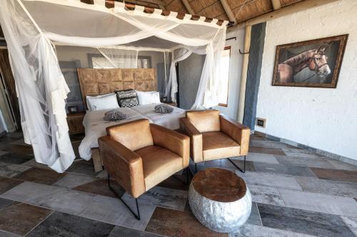 1 Schlafzimmer mit einem Bett und 2 Stühlen in der Unterkunft Desert Homestead Lodge in Sesriem