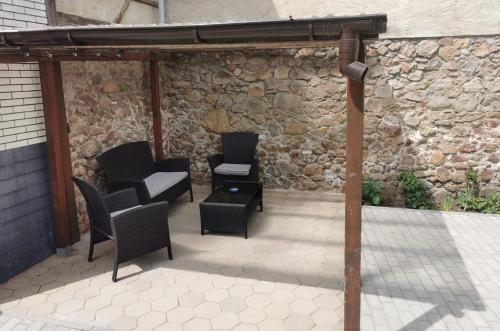 eine Terrasse mit Stühlen, Tischen und einer Steinmauer in der Unterkunft Schmetterling Zimmer in Bad Lausick